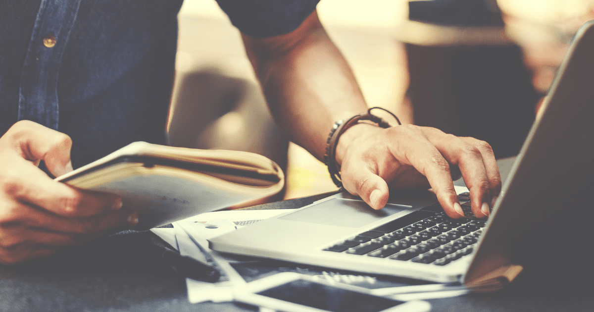 3 tips for streamlining your business processes Man works on laptop and looks at notepad, suggesting he is streamlining business processes using mind mapping software