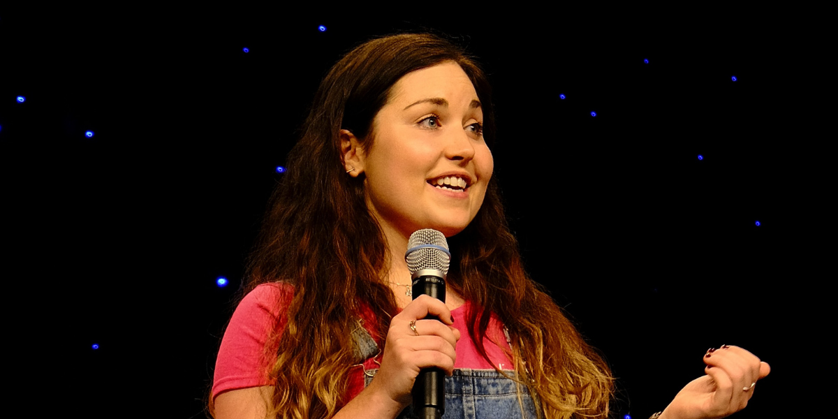 Tess holding a microphone and speaking at a WordCamp