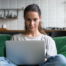 Woman remote working on laptop with legs crossed on sofa